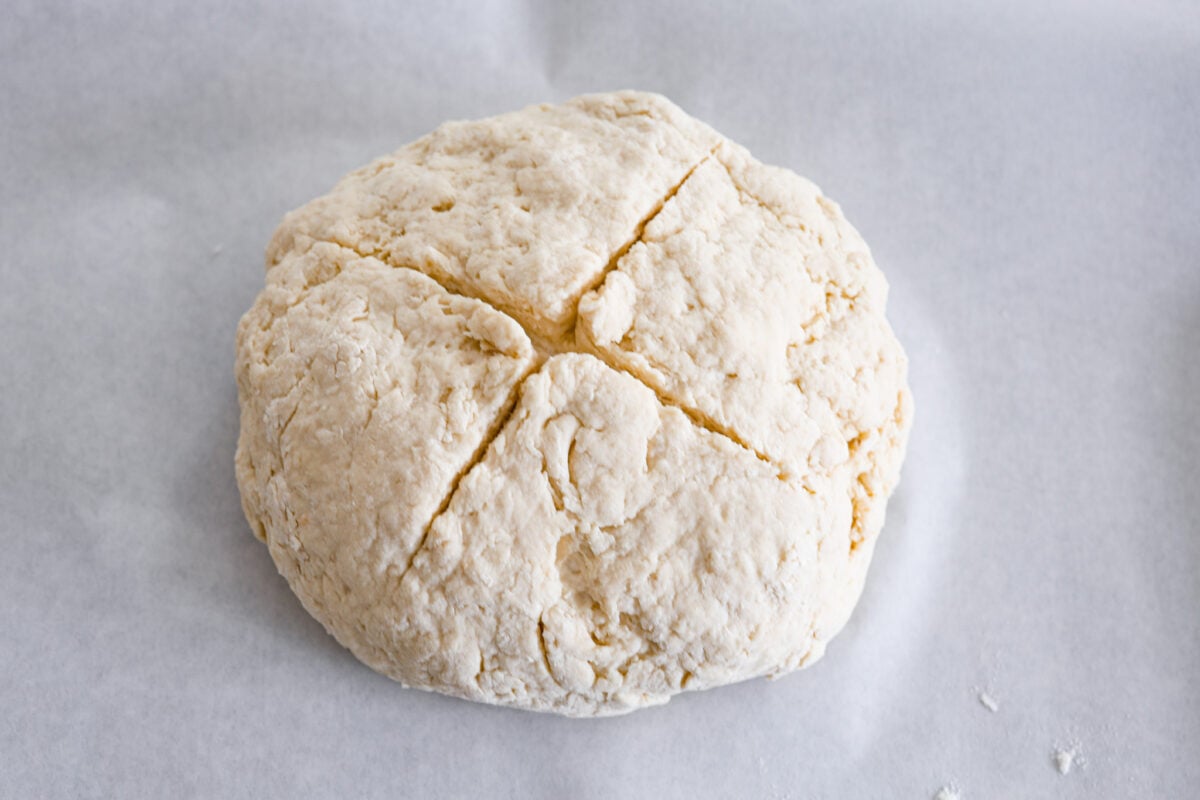An unbaked soda bread loaf, shaped and ready to be put in the oven.