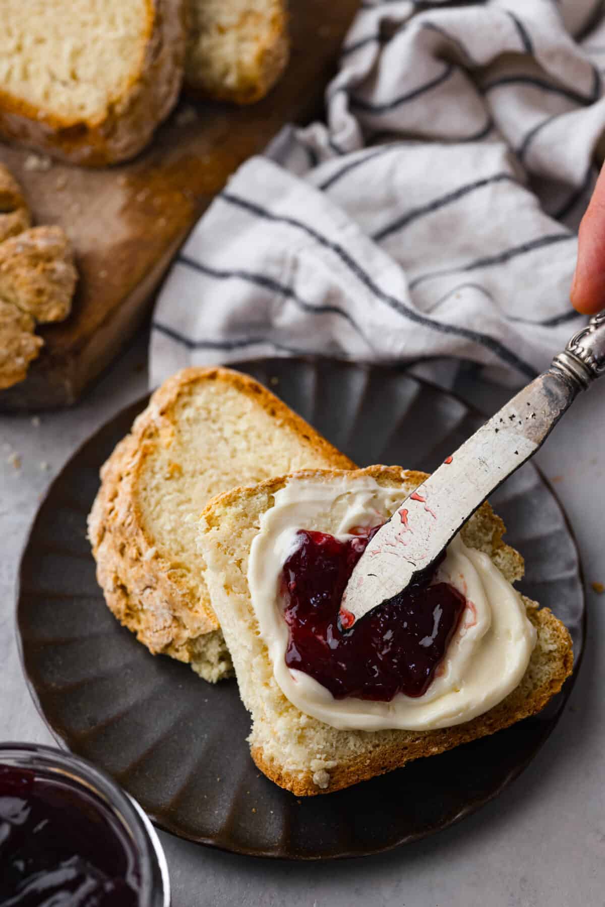 Spreading butter and jam over a slice of bread.