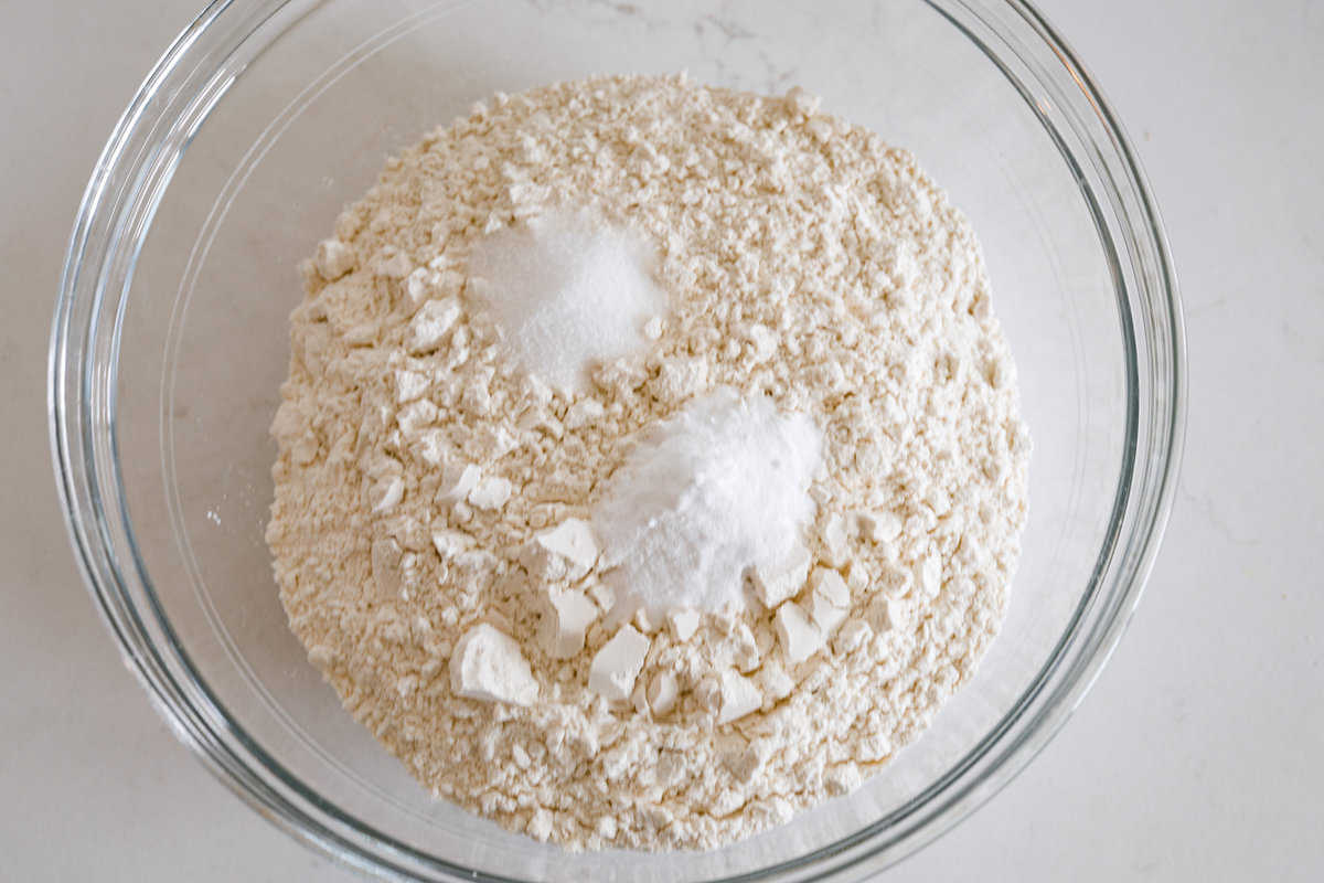 This Irish soda bread recipe uses just 4 pantry staples for a warm, crusty loaf that's perfect for slathering with butter and jam, or soaking up your favorite soup. No kneading required! Soda bread dough ingredients in a glass bowl.