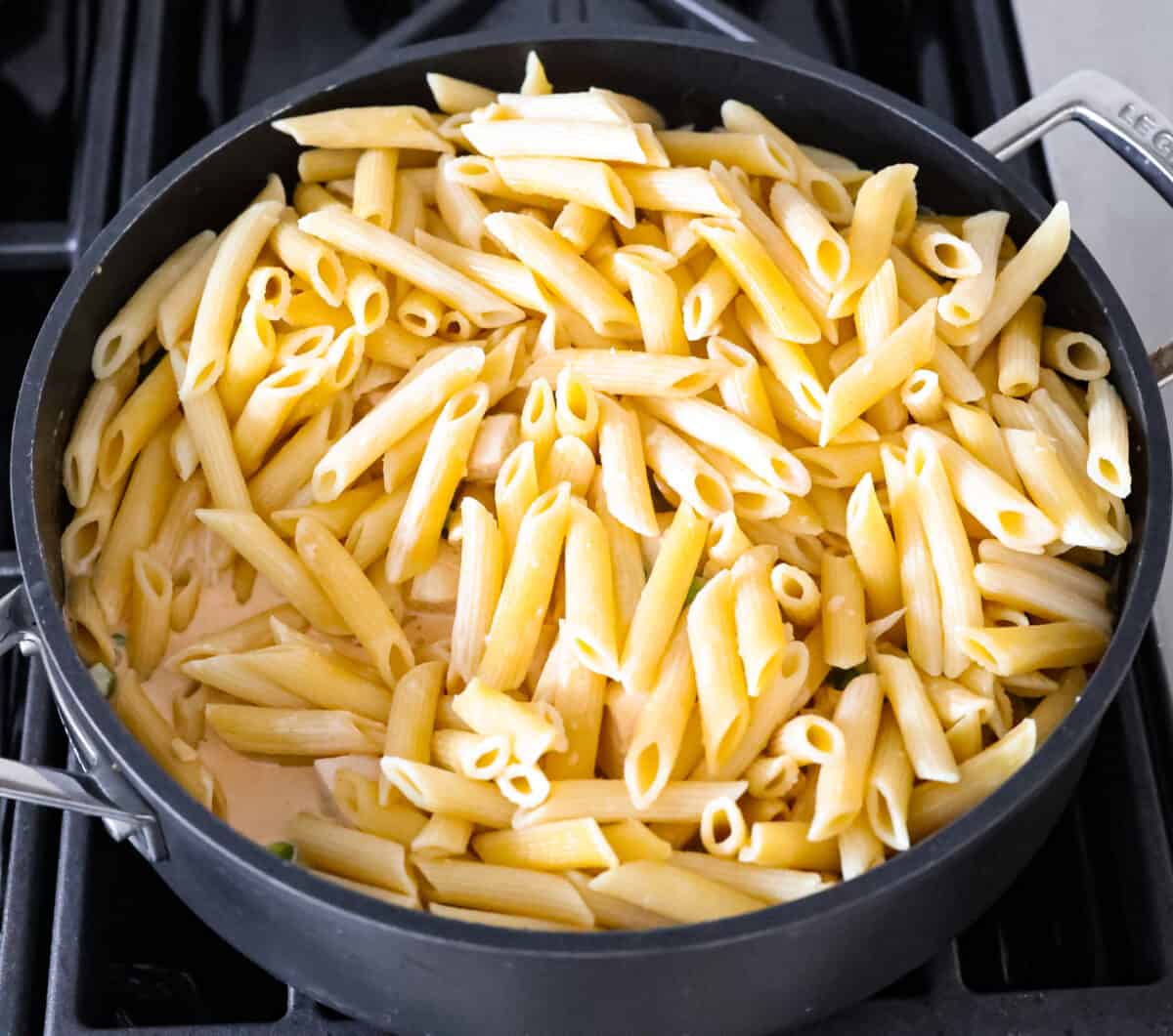Stirring in the cooked penne pasta.