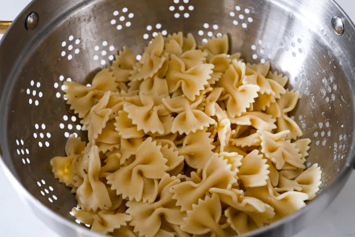 The cooked bowtie pasta being strained.