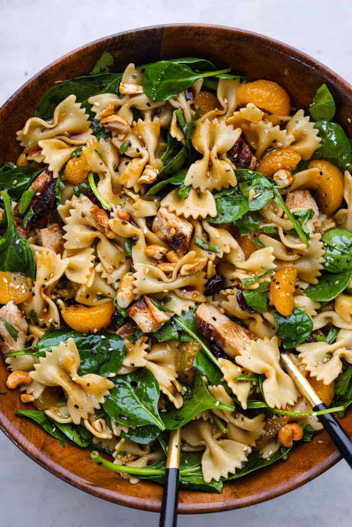 Teriyaki spinach pasta salad served in a large wooden serving bowl.