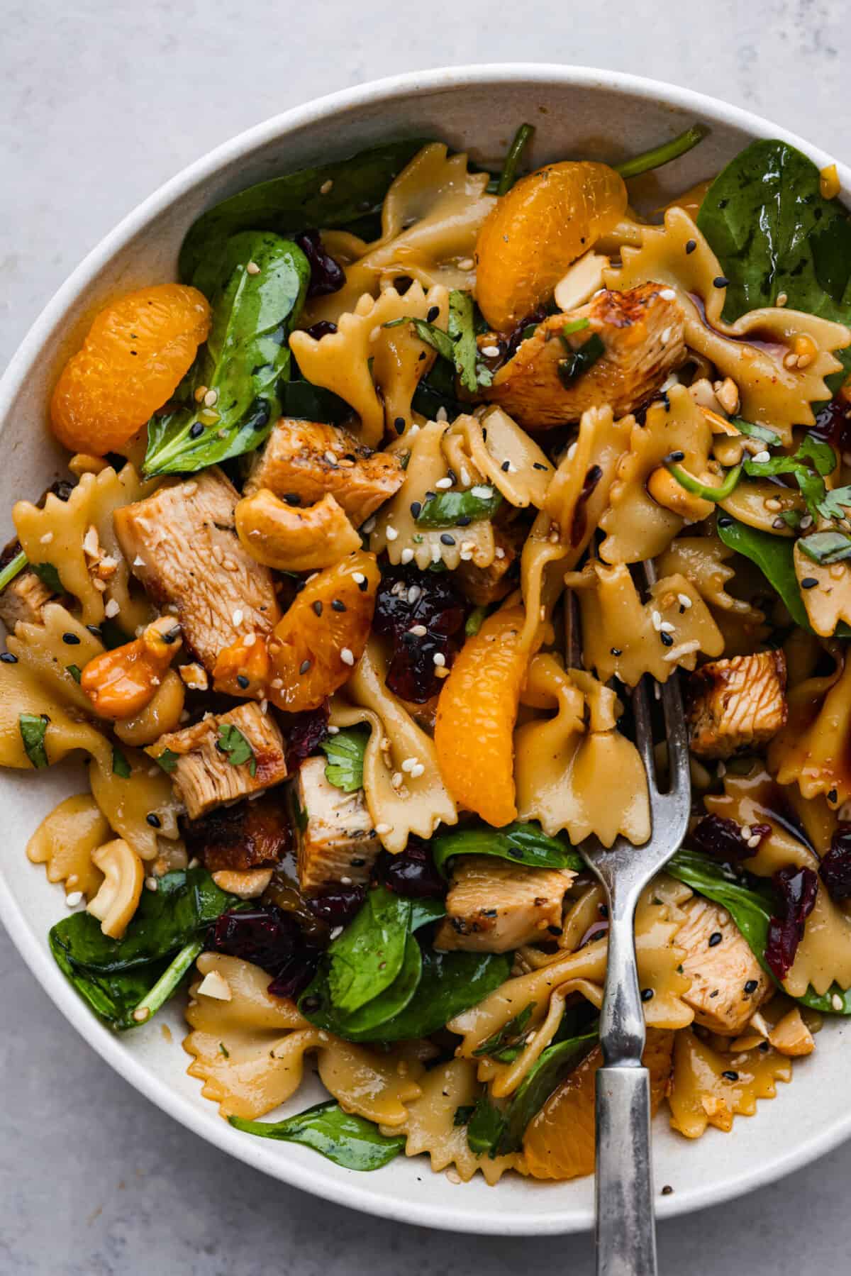 A serving of teriyaki spinach pasta salad on a white plate.