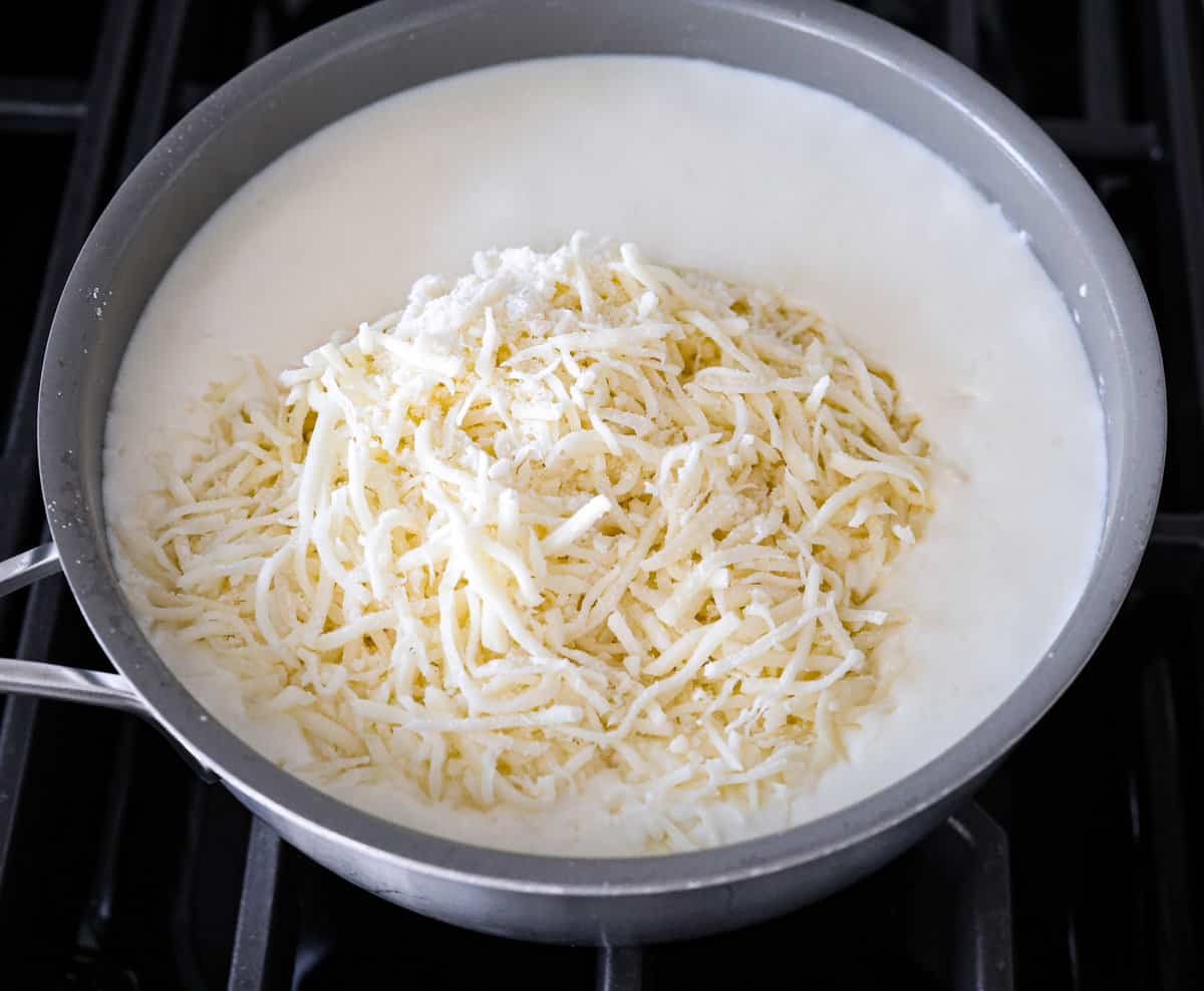 This white lasagna recipe swaps out traditional marinara for a homemade alfredo sauce that’s too good to resist. Packed with tender spinach, ricotta cheese, and Italian sausage, each bite is a dream! Melting the cheese and cream together.
