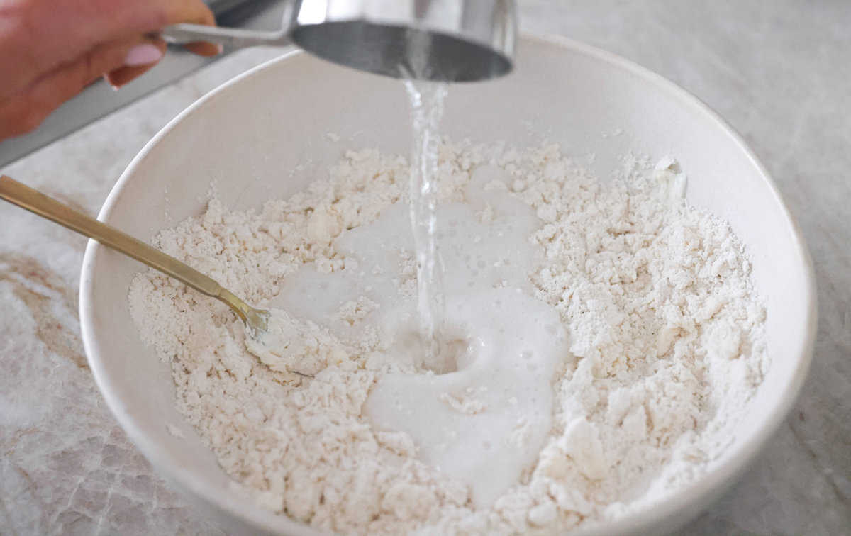 Tender and fluffy 7-up biscuits rise to perfection and instantly become everyone's favorite biscuit! It only takes 4-ingredients to create this melt-in-your-mouth biscuit recipe! Second process photo of the 7 up pouring into the dough.