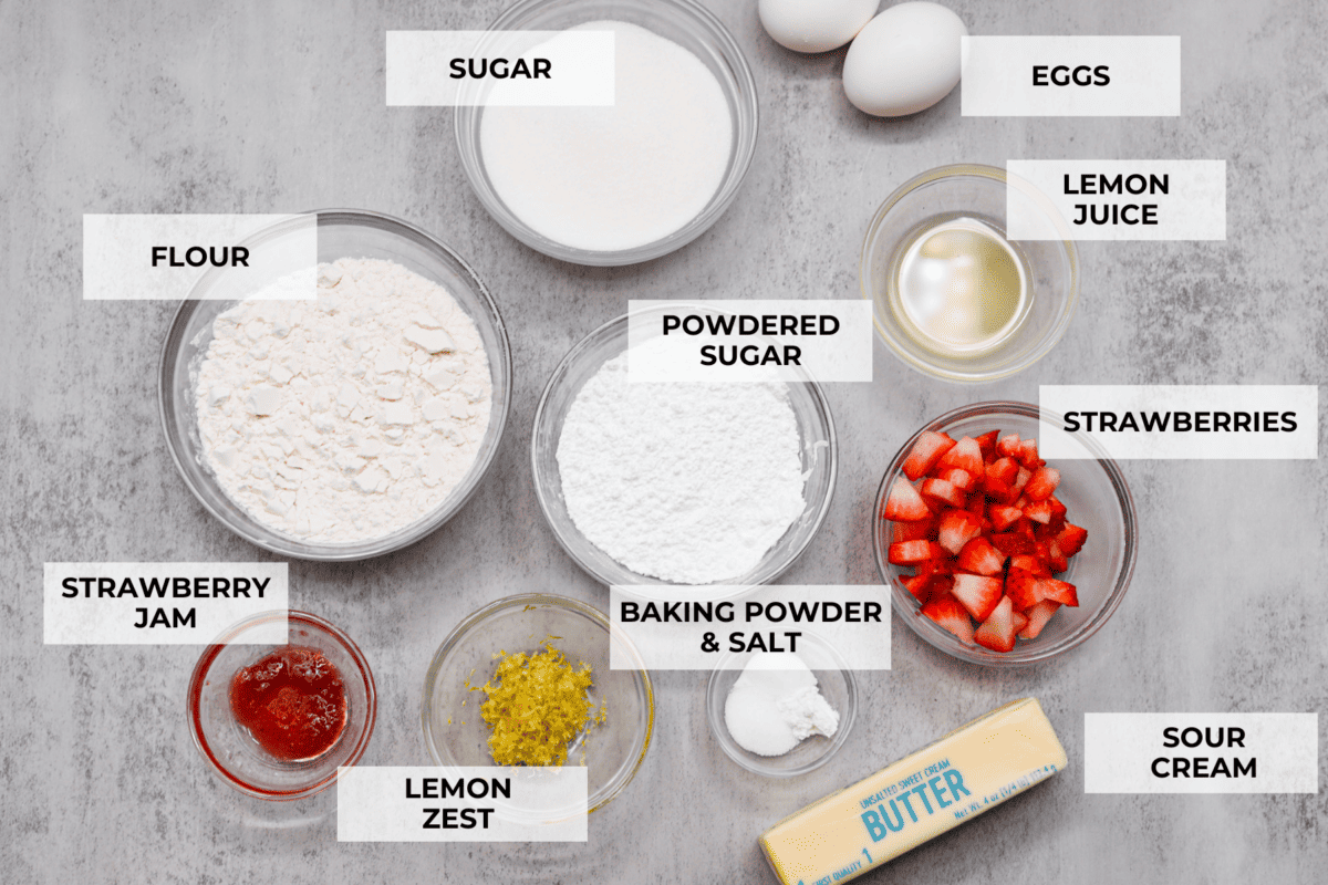 All of the ingredients to make the blondies. Listed are: sugar, flour, powdered sugar, eggs, lemon juice, strawberries, lemon zest, strawberry jam, baking powder and salt, and sour cream.
