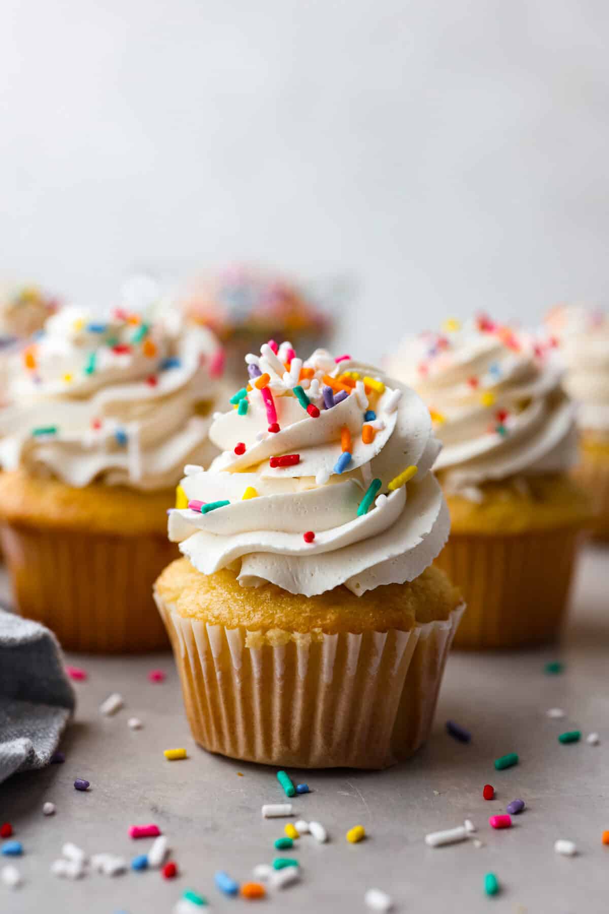 A cupcake frosted with meringue buttercream and topped with multicolored sprinkles