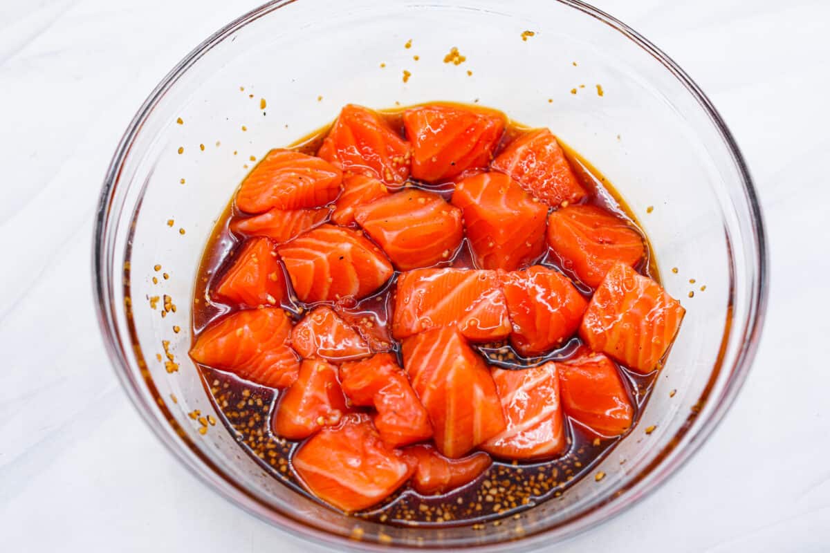Salmon bites in a glass bowl with marinade. 