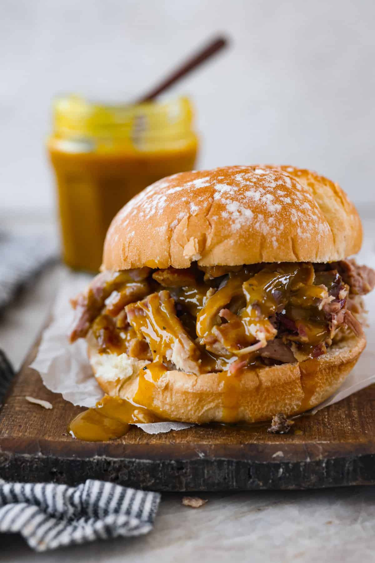 Smoky, tangy, and sweet, your taste buds will be begging you for more of this Mustard BBQ Sauce! It's the perfect addition to your summer cookouts this year, adding the best flavor to grilled meats! A pulled pork sandwich made with the mustard bbq sauce.