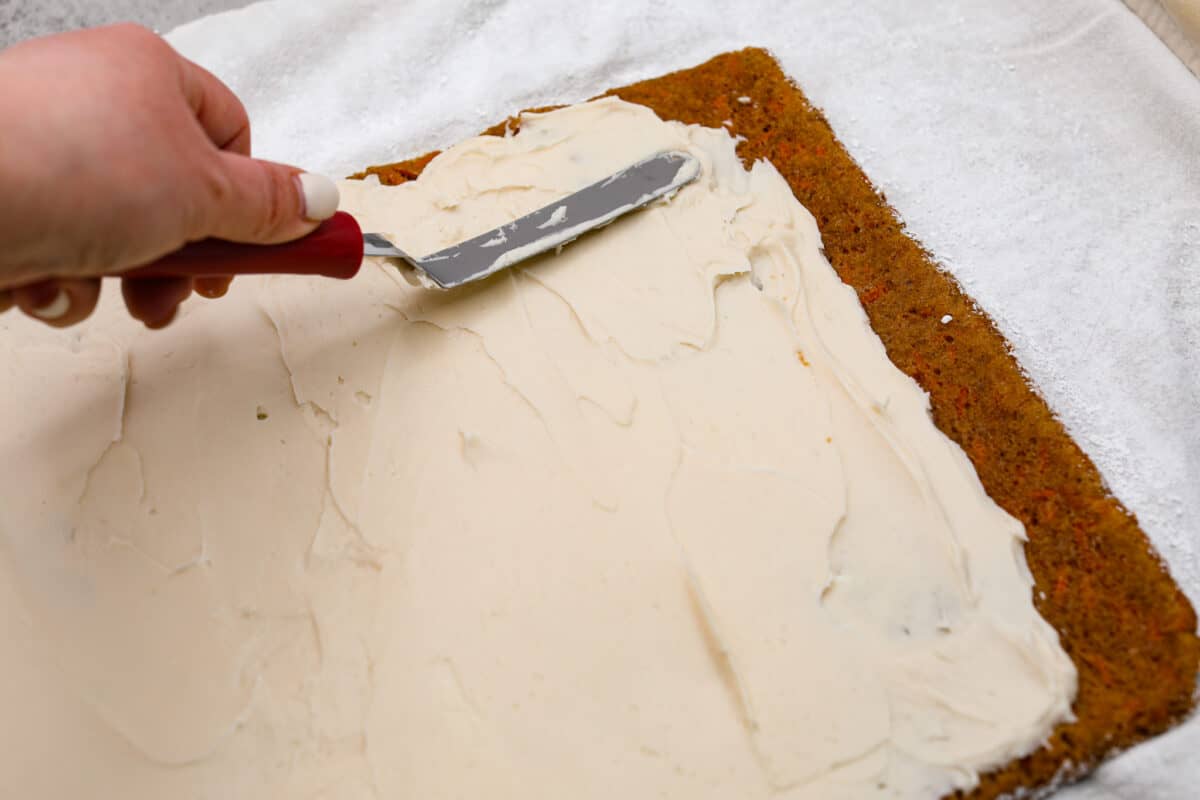 Spreading the cream cheese filling over the cake