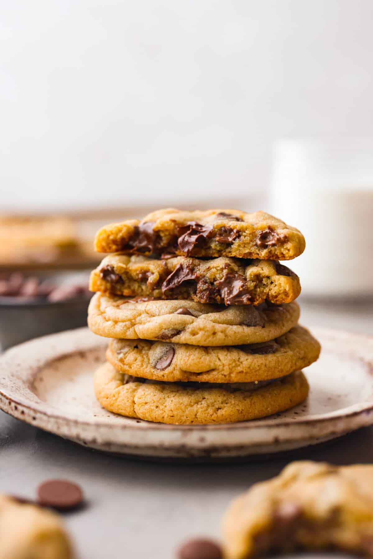Close side view of chocolate chip pudding cookies stacked on a plate with the top two cookies bitten into.
