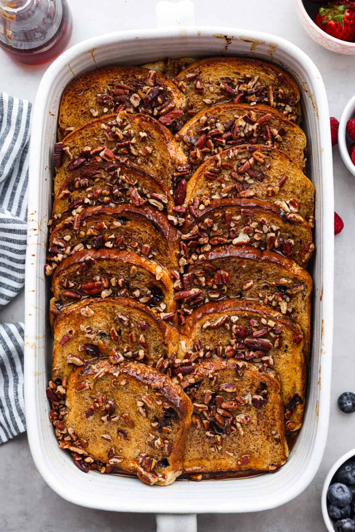 Baked French toast in a baking dish, topped with pecans.