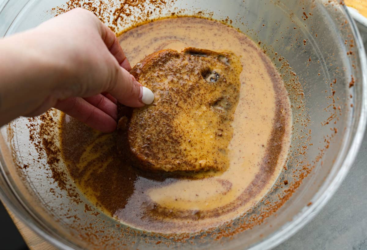 Cinnamon French toast bake is a warm and satisfying breakfast that's loaded with soft and sweet spiced bread all drizzled in maple syrup. Your family will go crazy over this insanely delicious (and easy-to-make) breakfast! Dredging a slice of bread in the egg mixture.