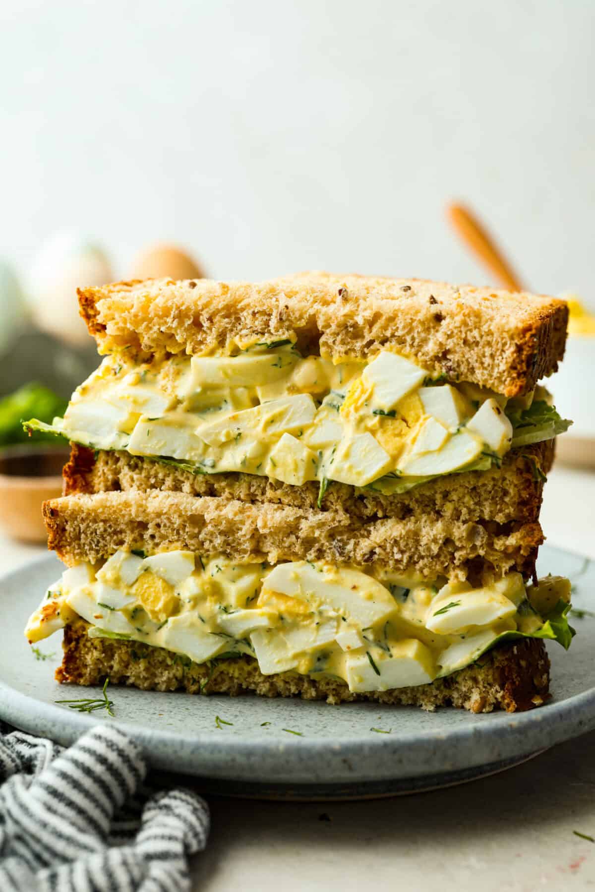 The side view of a sliced egg salad sandwich stacked on each other. 