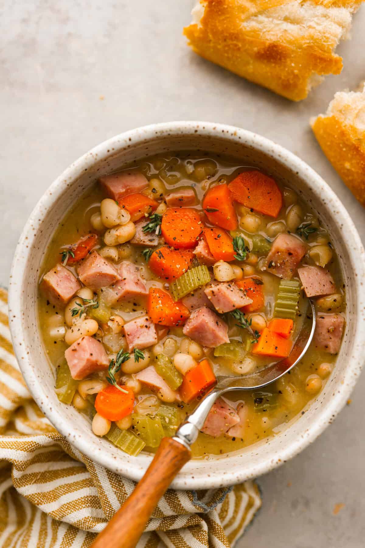 Close view of ham and bean soup in a bowl with a spoon.