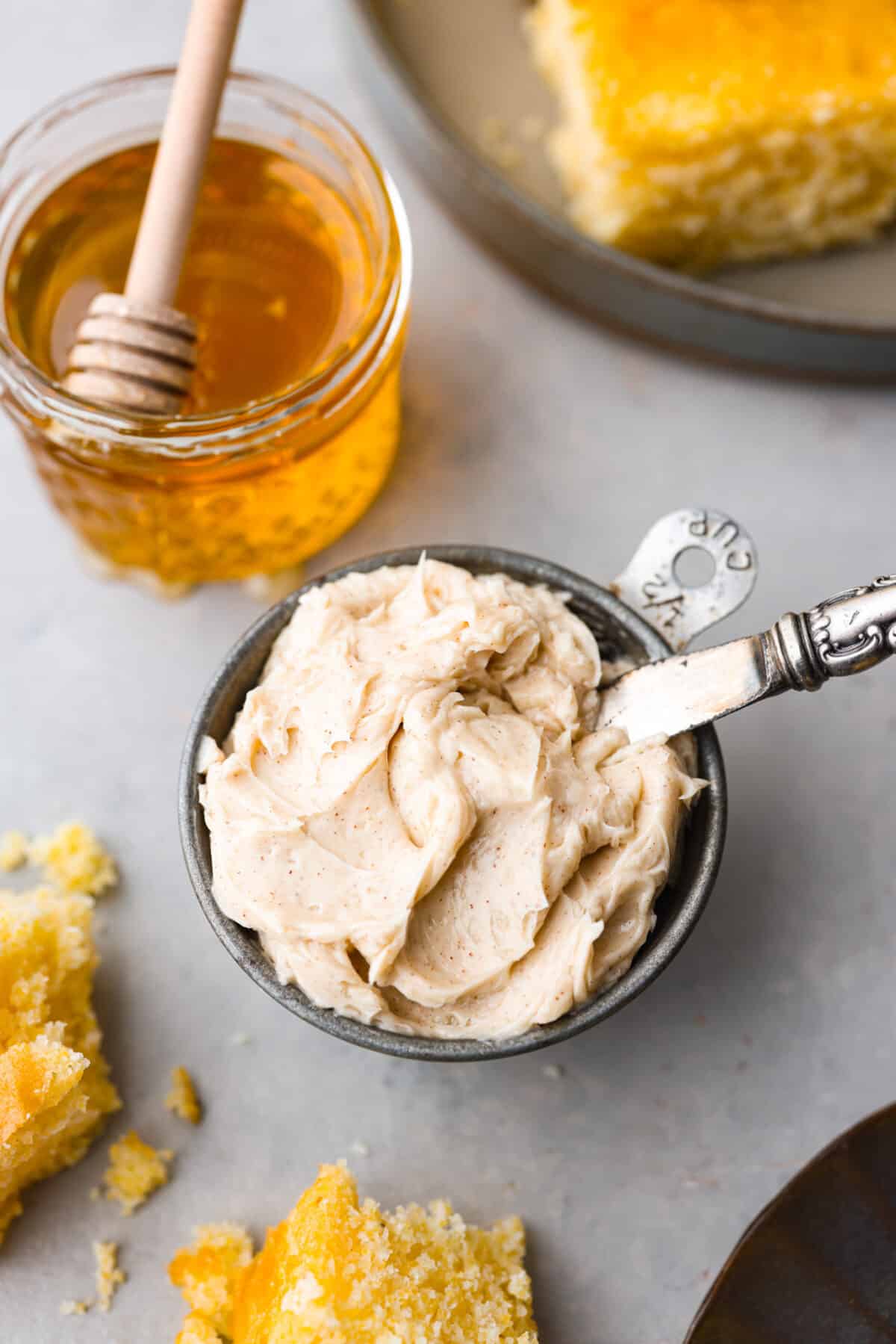 A small bowl of honey butter next to a jar of honey.