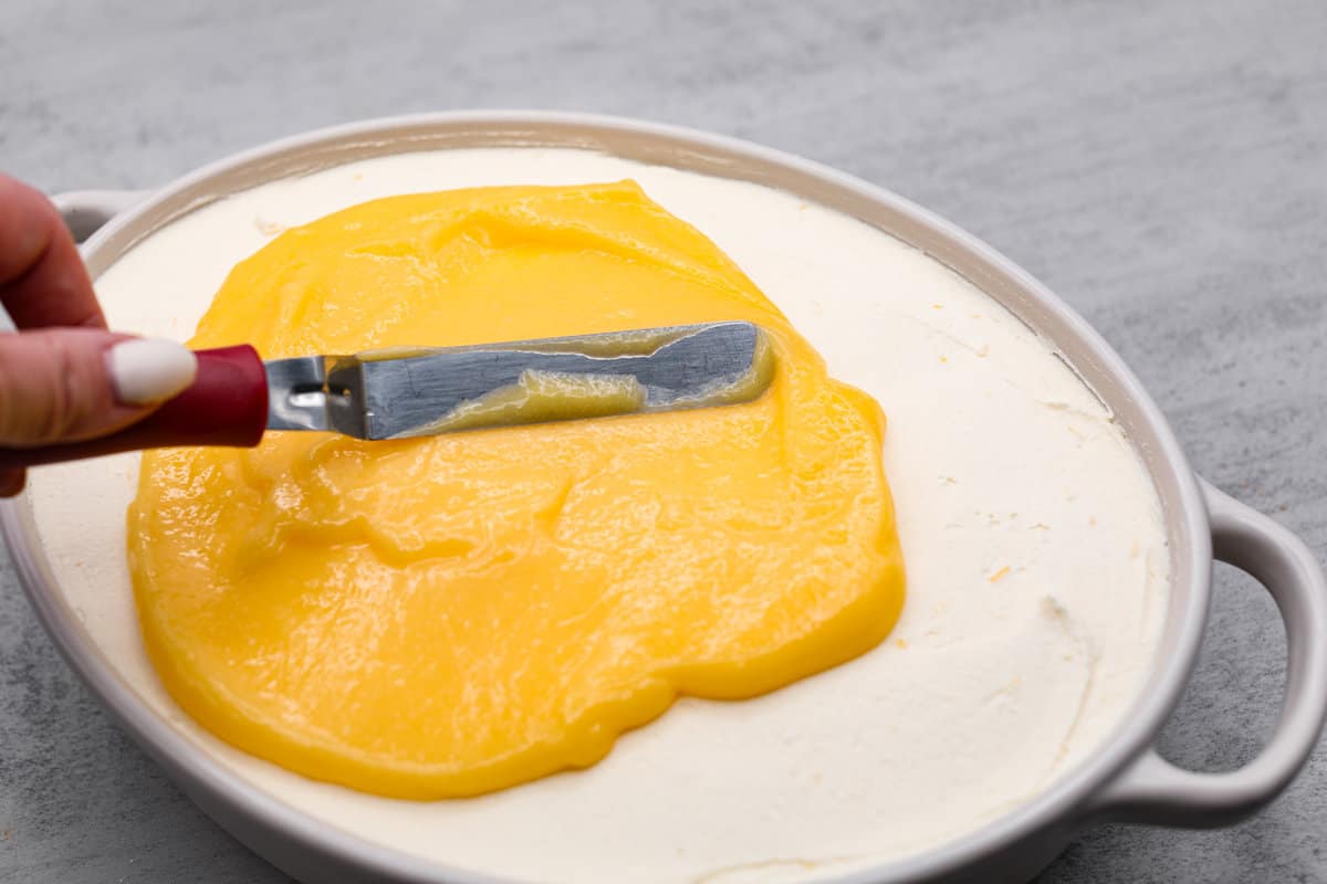Meet lemon tiramisu! The most amazing citrusy twist on a classic Italian dessert. The layers of mascarpone cream and lemon curd will have you reaching for another slice! Topping off the lemon tiramisu with lemon curd.
