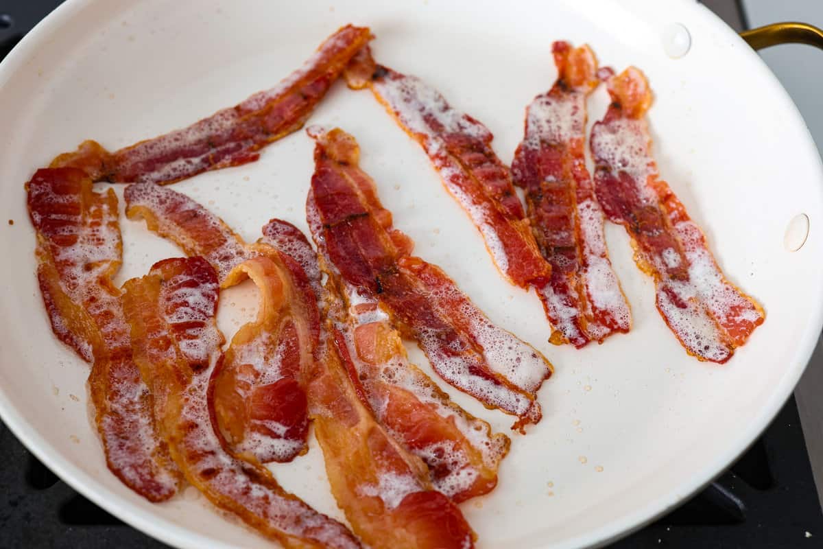 Sheet pan eggs are not only fluffy and full of flavor, but the best way to meal prep eggs or feed a crowd! Add your favorite mix-ins and serve as-is or use them to make breakfast sandwiches or as a topping for avocado toast! The bacon for the sheet pan eggs being cooked.