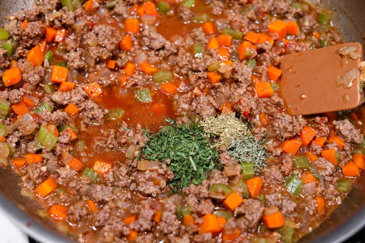 Preheat the oven to 375 degrees Fahrenheit. In a large, deep skillet, heat the oil over medium-high heat and cook the carrots, celery, and onion until softened, about 5 minutes. Add the beef and cook until thoroughly browned and no pink remains. Break it up into pieces as it cooks. Add the minced garlic and cook for 1 additional minute. Whisk together beef broth and cornstarch. Add it to the skillet, along with the tomato paste, Worcestershire sauce, herbs, and salt and pepper. Stir in the frozen peas and cook for 5 minutes, until the sauce has thickened. Mashed Potatoes Add the peeled and diced potatoes to a large pot and fill with cold water until the potatoes are covered. Add 2-3 large pinches of kosher salt. Place the pot over high heat and bring to a boil. Reduce heat to maintain a rolling boil and cook until tender, about 12-15 minutes. Drain the potatoes into a colander. Return the potatoes to the pot and either run them through a potato ricer or use a hand masher to mash them well. Add the butter, warm half and half, and Boursin cheese to the potatoes and mash until creamy. Taste and season with salt and pepper if needed. Spread the potatoes evenly over the top of the meat mixture. Bake the Shepherd's pie uncovered for 25-30 minutes until the edges are bubbling. Sprinkle with fresh chopped parsley and serve. Sauteeing the beef and vegetables.
