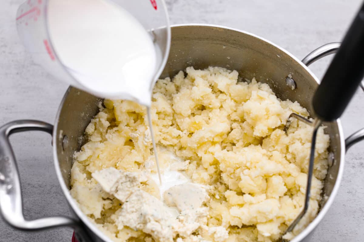 Mashing the potatoes and adding cream.