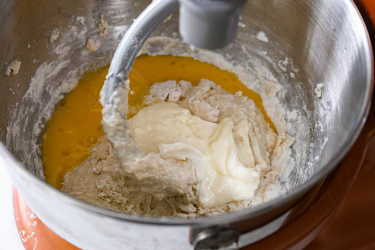 Third process photo of the flour, yeast, eggs, and butter kneading in a mixing bowl. 