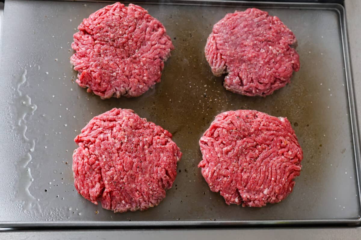 Burger meat shaped on a griddle. 