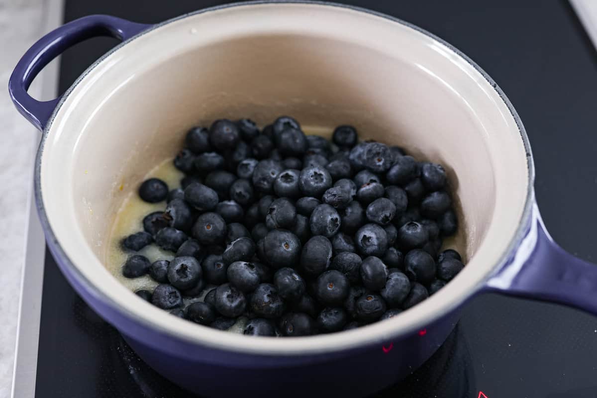 Be prepared to fall in love with this blueberry lemon upside-down cake! A delicious and moist lemon sponge cake bursting with juicy caramelized blueberries on top! Third photo of the blueberries stirring into the sauce.
