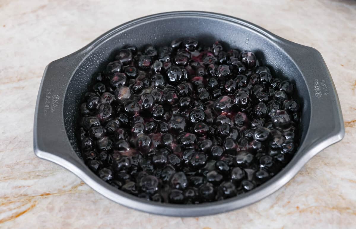 Be prepared to fall in love with this blueberry lemon upside-down cake! A delicious and moist lemon sponge cake bursting with juicy caramelized blueberries on top! Fourth photo of the blueberry and sauce mixture in the bottom of the pan.