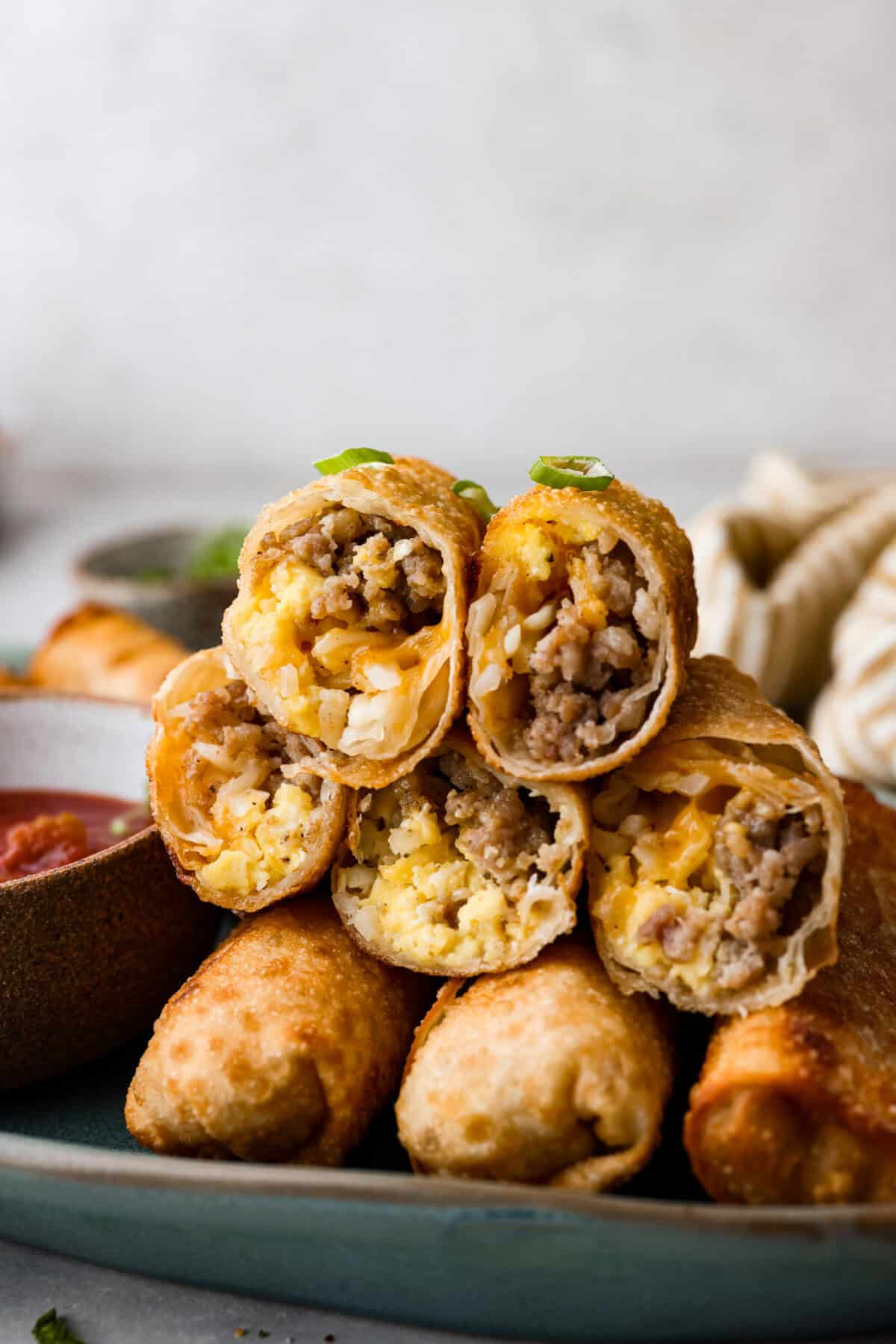 Side shot of stacked breakfast egg rolls, cut through middle so you can see the inside.