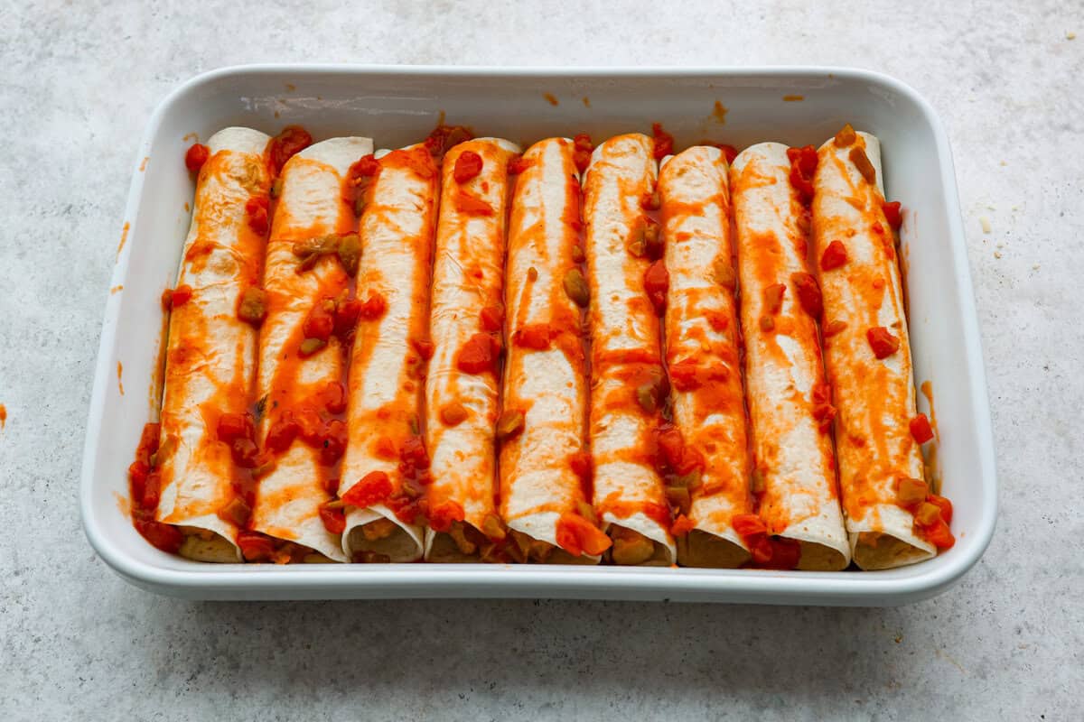 A new enchilada is in town! Get ready for the bold flavors in these buffalo chicken enchiladas! Chicken enchiladas loaded with cheese and smothered in a creamy buffalo enchilada sauce. Seventh photo of the sauce poured on top of the buffalo chicken enchiladas.