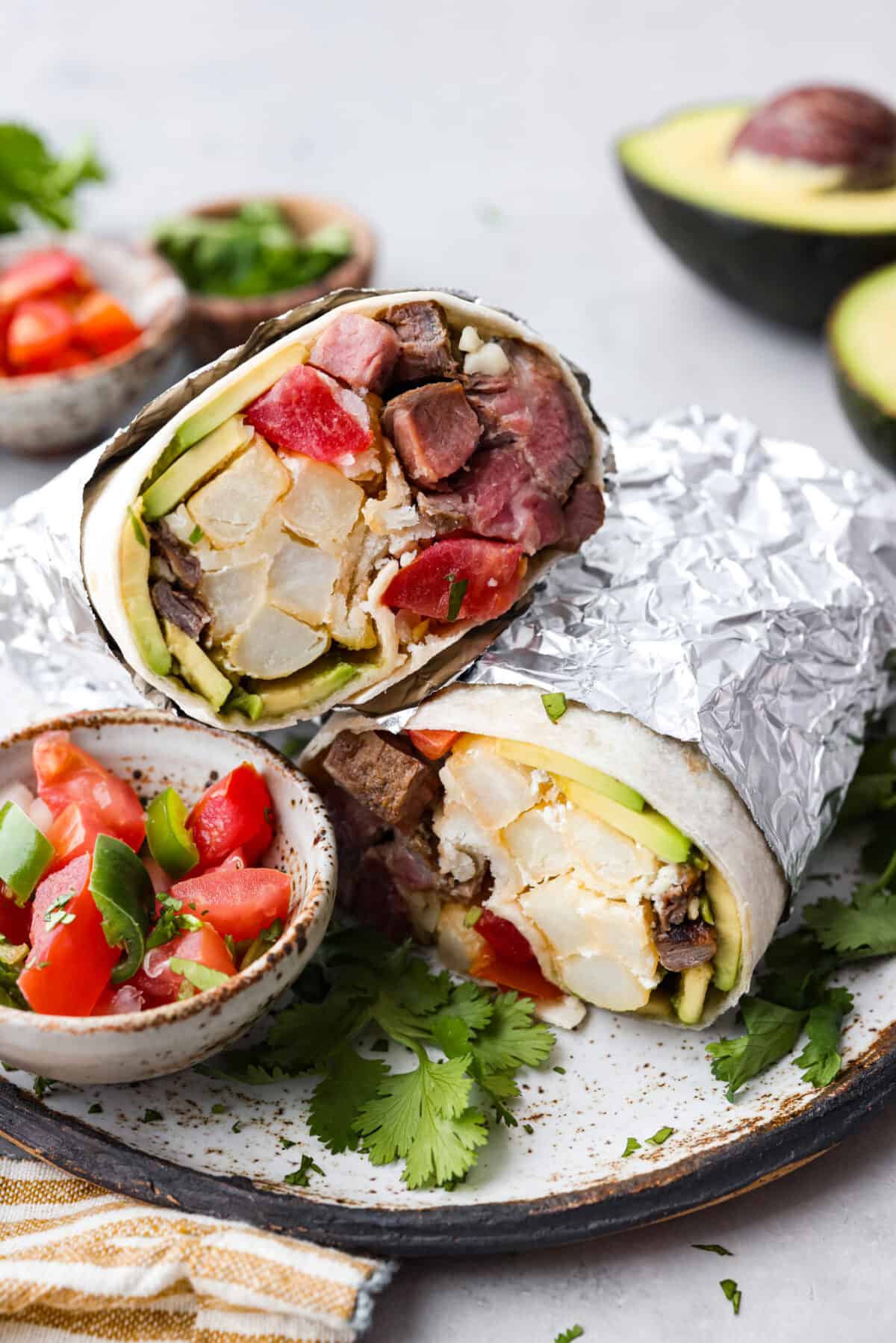 A california burrito wrapped in tinfoil and sliced in half. 