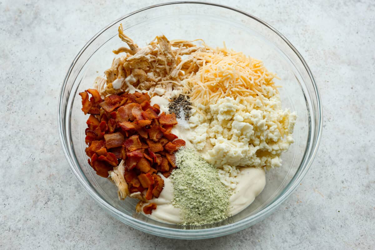 A glass bowl with all of the chicken and seasonings. 