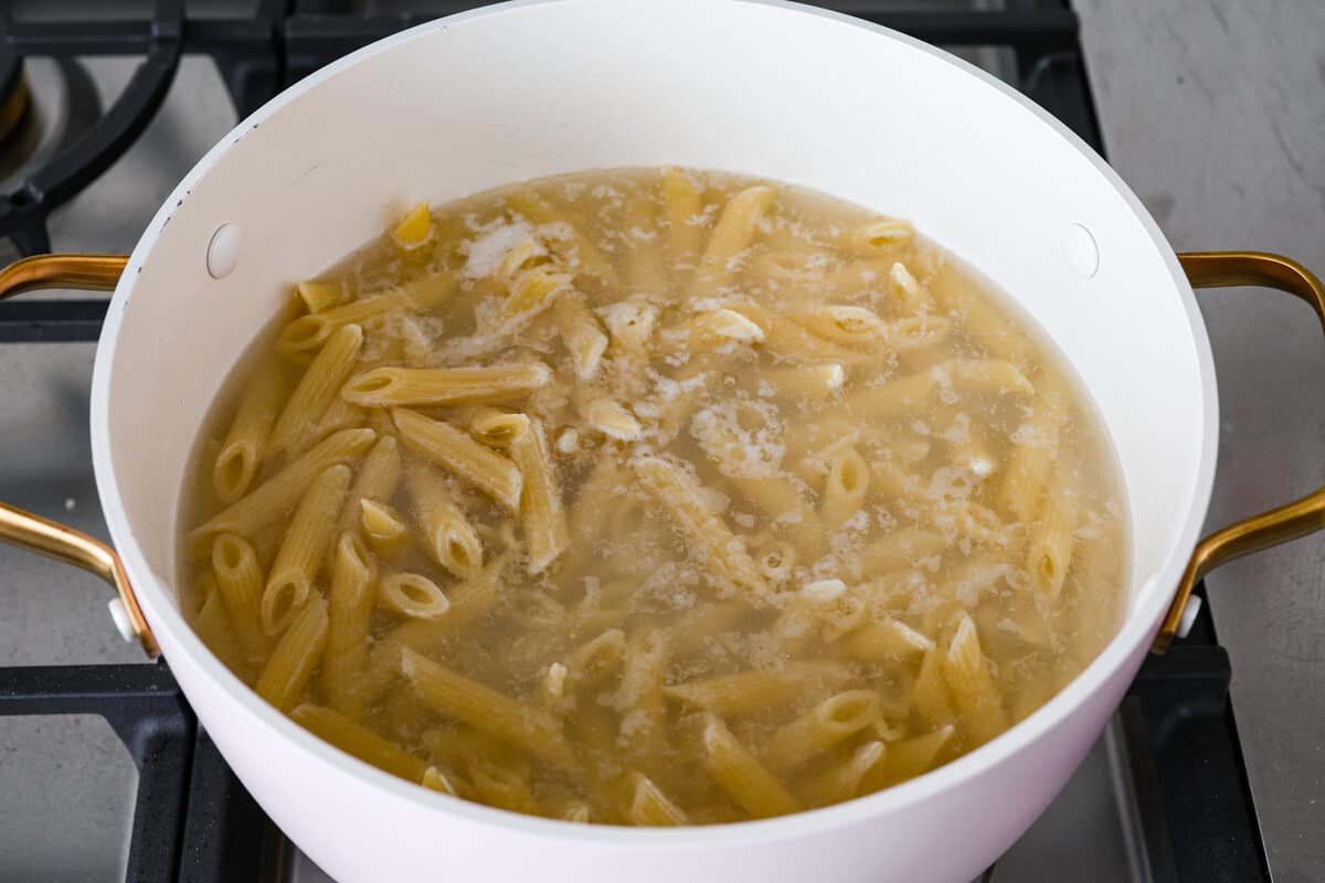 Chicken Bacon Ranch Casserole is a meal the whole family will gobble up in no time! It's super easy to make with a mix of pasta, bacon, shredded chicken, creamy ranch sauce and plenty of cheese. An irresistible dinner that's simple enough for busy weeknights! Penne pasta in water in a pot.
