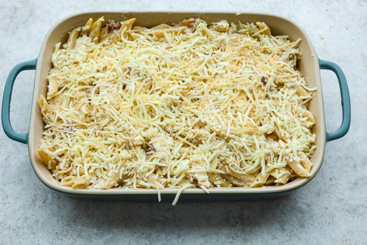 A baking dish with the ingredients and topped with cheese. 