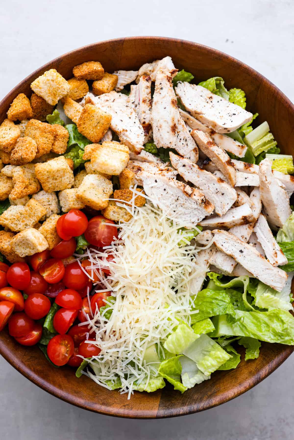 Grilled chicken caesar salad in a bowl.  ready to be mixed. 