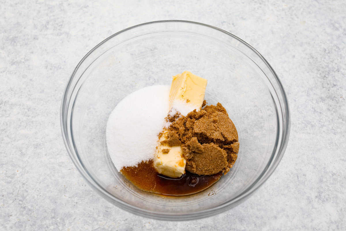 I am so excited about this recipe, it combines two of my all-time favorite desserts, cookie dough and cheesecake! With the rich Oreo crust, creamy cheesecake filling, and edible cookie dough bites, this no-bake cookie dough cheesecake will have your taste buds begging for more! Overhead shot of sugar and butter in a bowl