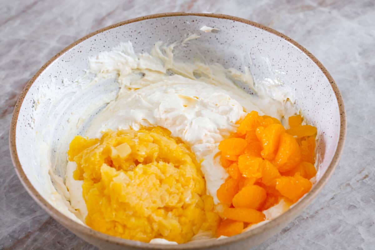 Third process photo of pineapple and mandarin oranges added to the pudding mixture.