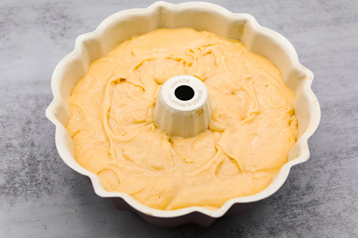 This Cream Cheese Pound Cake is a tender, moist, and flavorful dessert that's a new spin on traditional pound cake. Plus, it’s super simple to make! Top it off with whipped cream and fresh berries or enjoy plain! Pouring the cream cheese pound cake batter into a bundt pan.