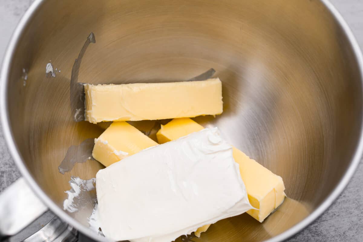 The cream cheese and butter being added to a mixing bowl.