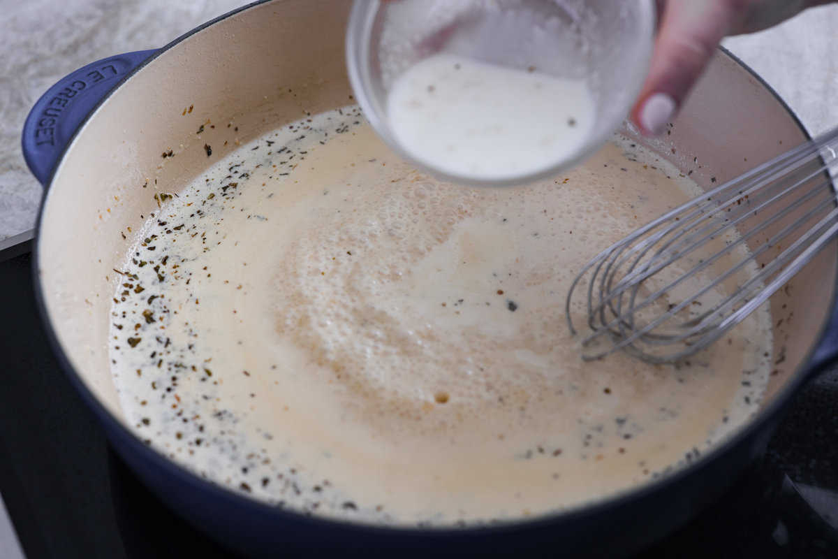 Creamy Lemon Parmesan Chicken is an incredible restaurant-quality meal you can make in under 30 minutes. Tender, juicy chicken is smothered in a creamy lemon parmesan sauce- it’s a meal the family will go crazy for! Adding the sauce ingredients to the skillet.
