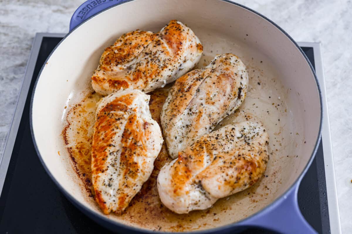 Searing the chicken in a skillet. 