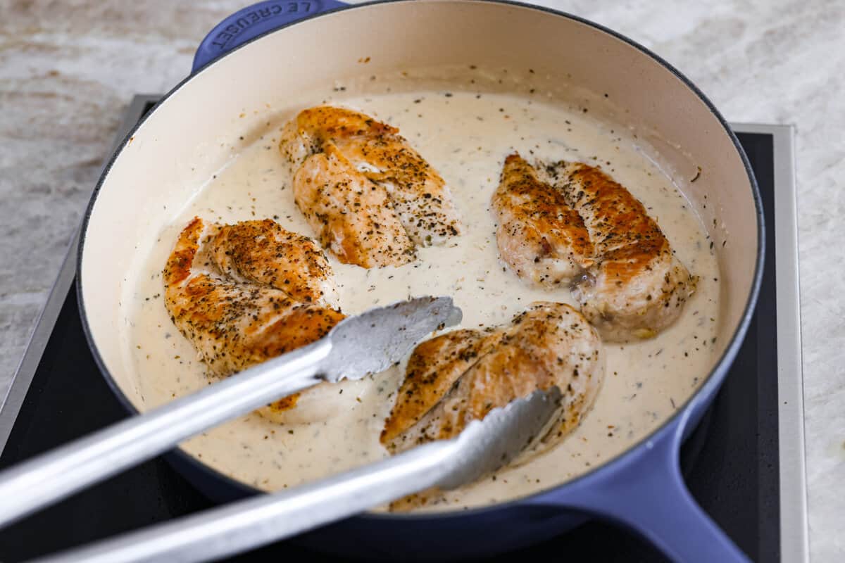 Creamy Lemon Parmesan Chicken is an incredible restaurant-quality meal you can make in under 30 minutes. Tender, juicy chicken is smothered in a creamy lemon parmesan sauce- it’s a meal the family will go crazy for! Combining the sauce with the cooked chicken.