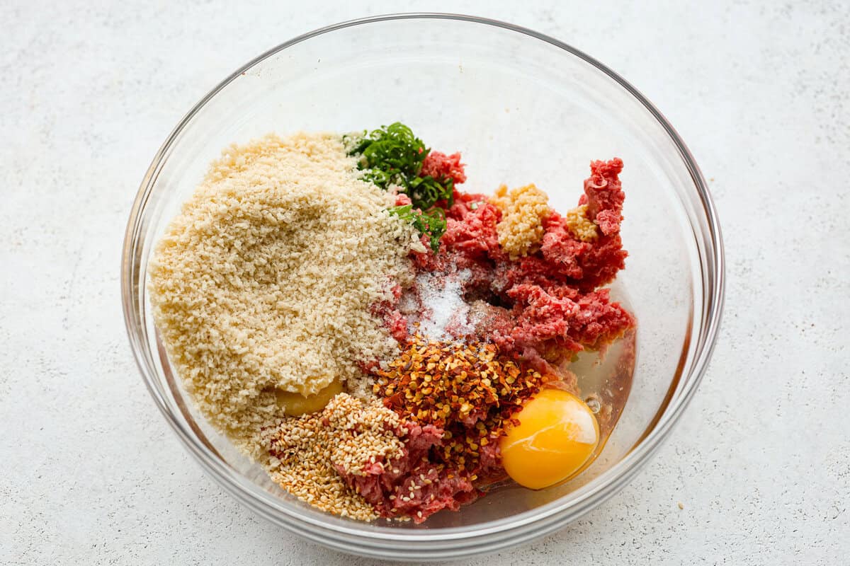 Get ready to spice up your dinner with these firecracker meatballs! Juicy beef meatballs are baked to perfection and then tossed in a sweet and spicy buffalo-based sauce, creating a delicious meal that's perfect for any night of the week. A bowl of unmixed ingredients.