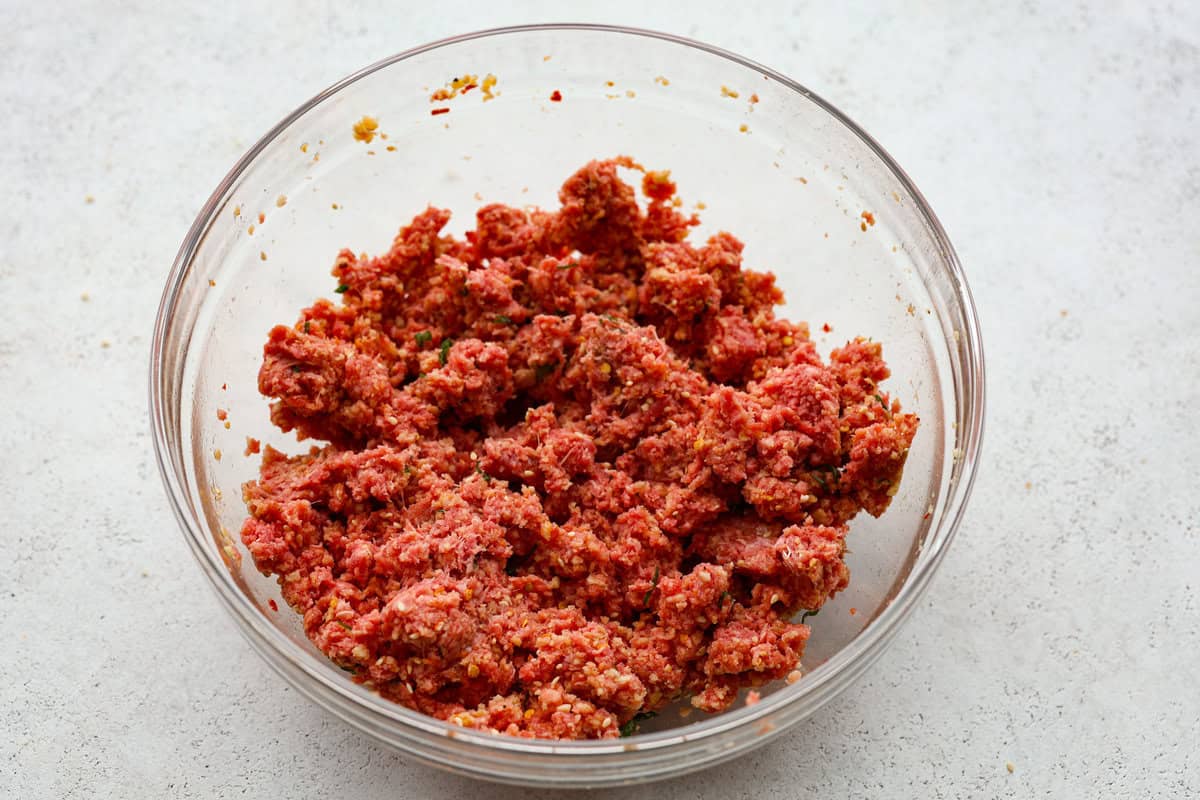 Get ready to spice up your dinner with these firecracker meatballs! Juicy beef meatballs are baked to perfection and then tossed in a sweet and spicy buffalo-based sauce, creating a delicious meal that's perfect for any night of the week. Overhead shot mixed ingredients.