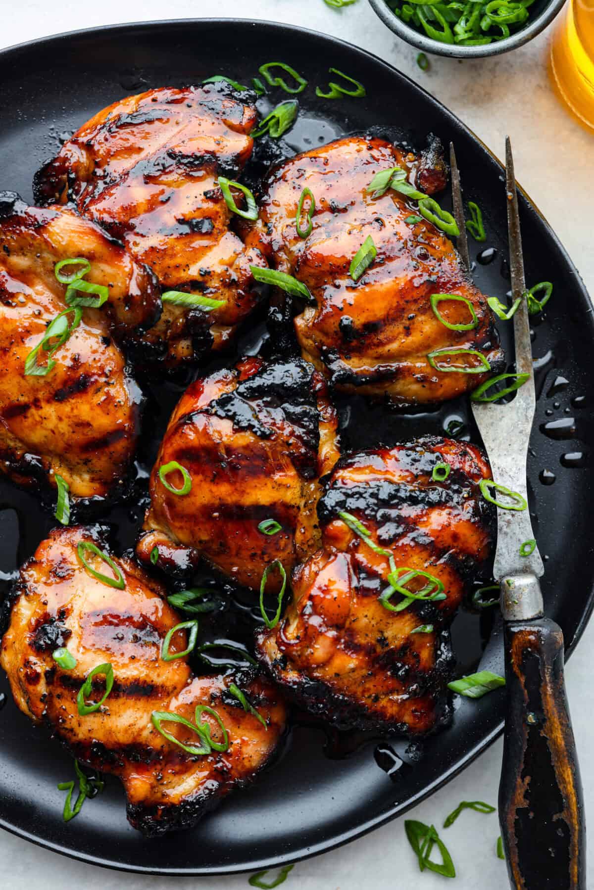 Grilled bourbon chicken on a black plate. 