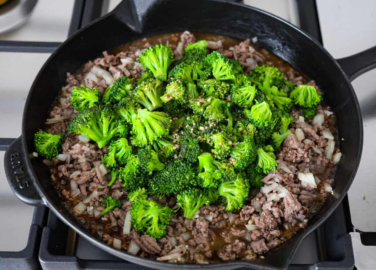 Overhead shot of a skillet with beef, onions and broccoli with sauce. 