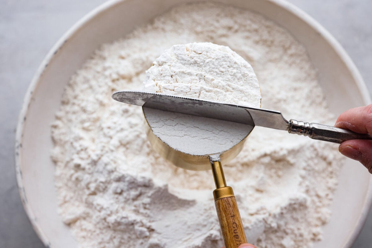 A picture of a knife sweeping off excess flour to show how to properly measure baking ingredients. 