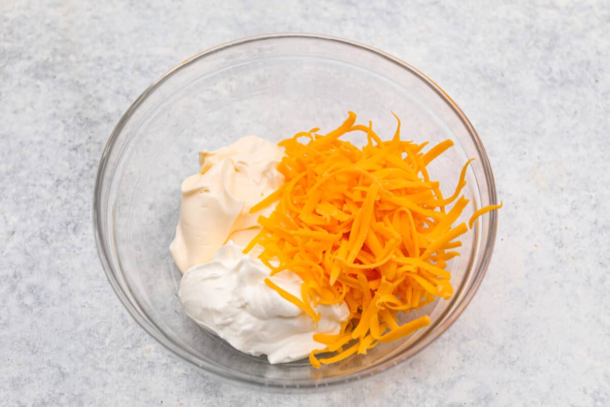 Sour cream, mayonnaise and cheese in a glass bowl. 