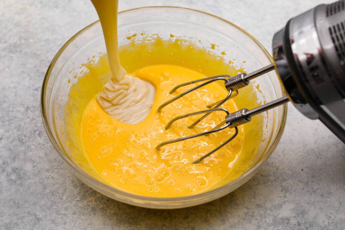 Third photo of the beaten egg yolks and the sweetened condensed milk pouring in.