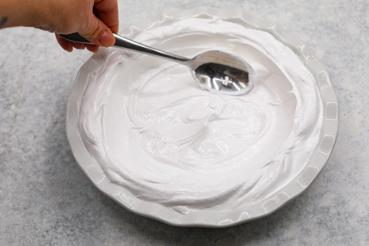 Second process photo of the meringue spread inside the pie dish.